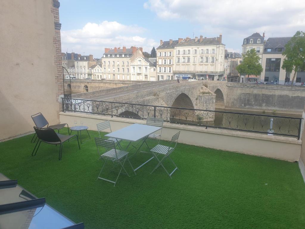 a table and chairs on a balcony with green grass at Appartement cosy face à la Mayenne in Laval