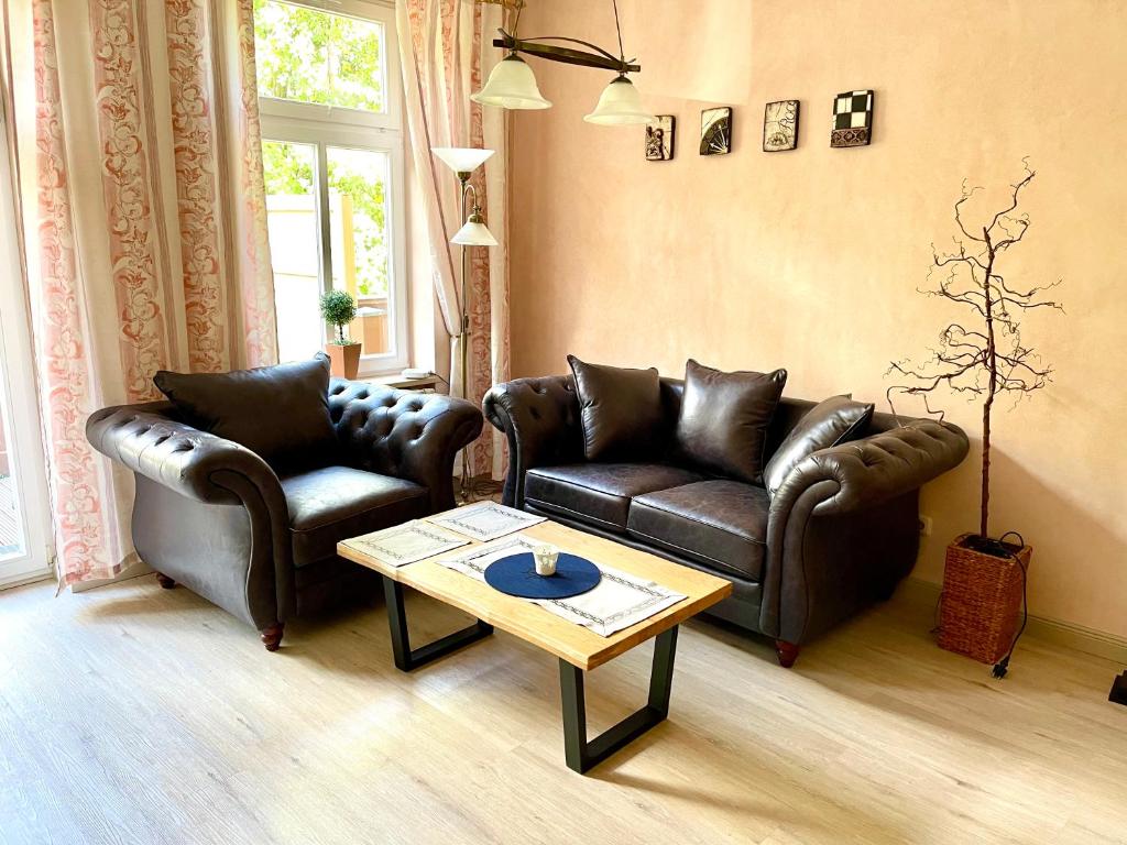 Sala de estar con 2 sofás de cuero y mesa de centro en Villa Käthe FeWo Nr.4 en Kühlungsborn