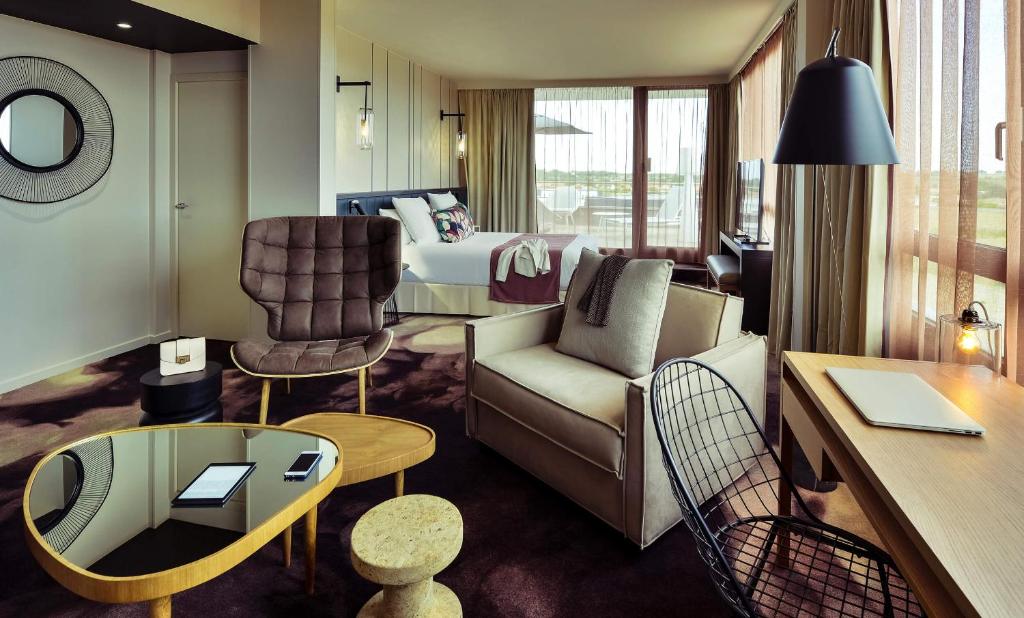 une chambre d'hôtel avec un canapé et un lit dans l'établissement Mercure Lyon Genas Eurexpo, à Genas