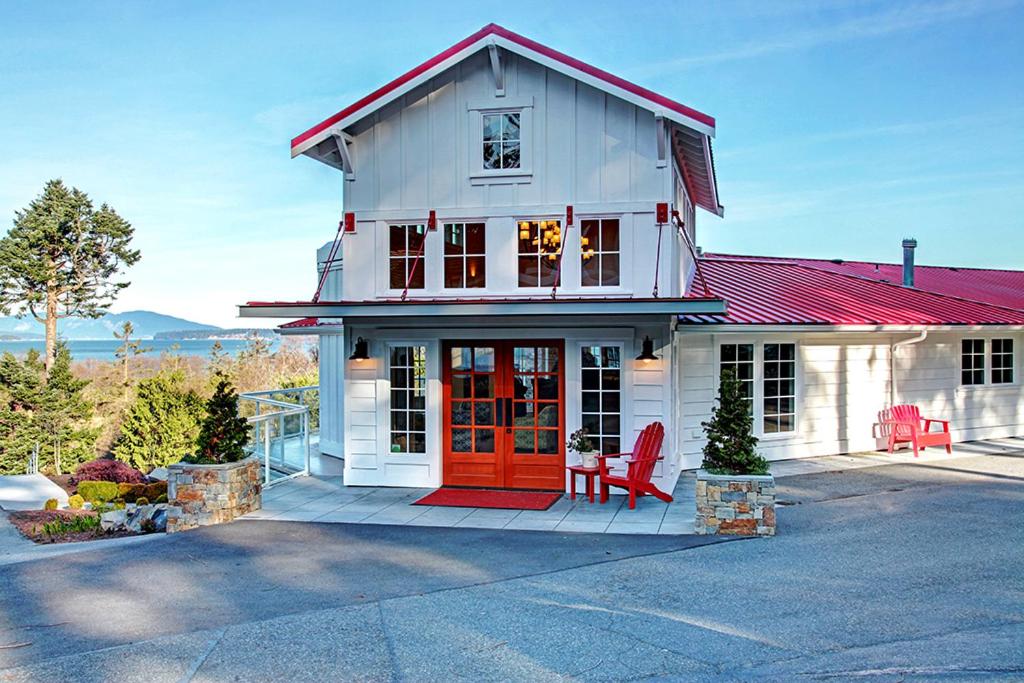 a white house with a red door and a red chair at Anacortes Ship Harbor Inn in Anacortes