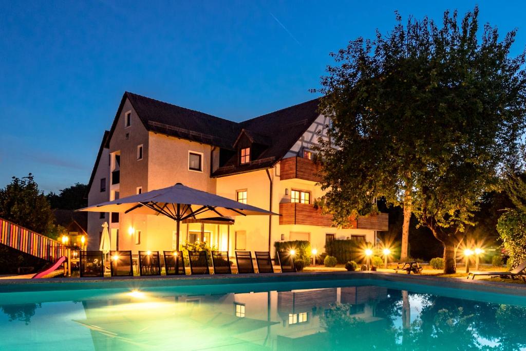 a large house with a swimming pool at night at Familienhotel Friedrichshof in Obertrubach