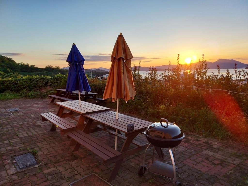 two umbrellas and a grill on a picnic table with the sunset at Aquarius Building I 2043 in Geoje