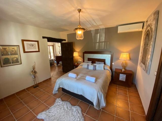 um quarto com uma cama grande e piso em azulejo em Luxury Spanish Country House close to Granada & Sierra Nevada em Ermita Nueva