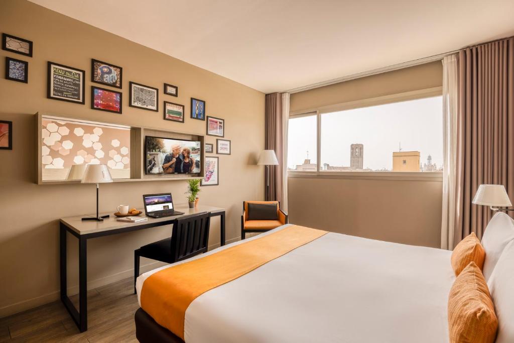 a hotel room with a bed and a desk and a window at Citadines Ramblas Barcelona in Barcelona