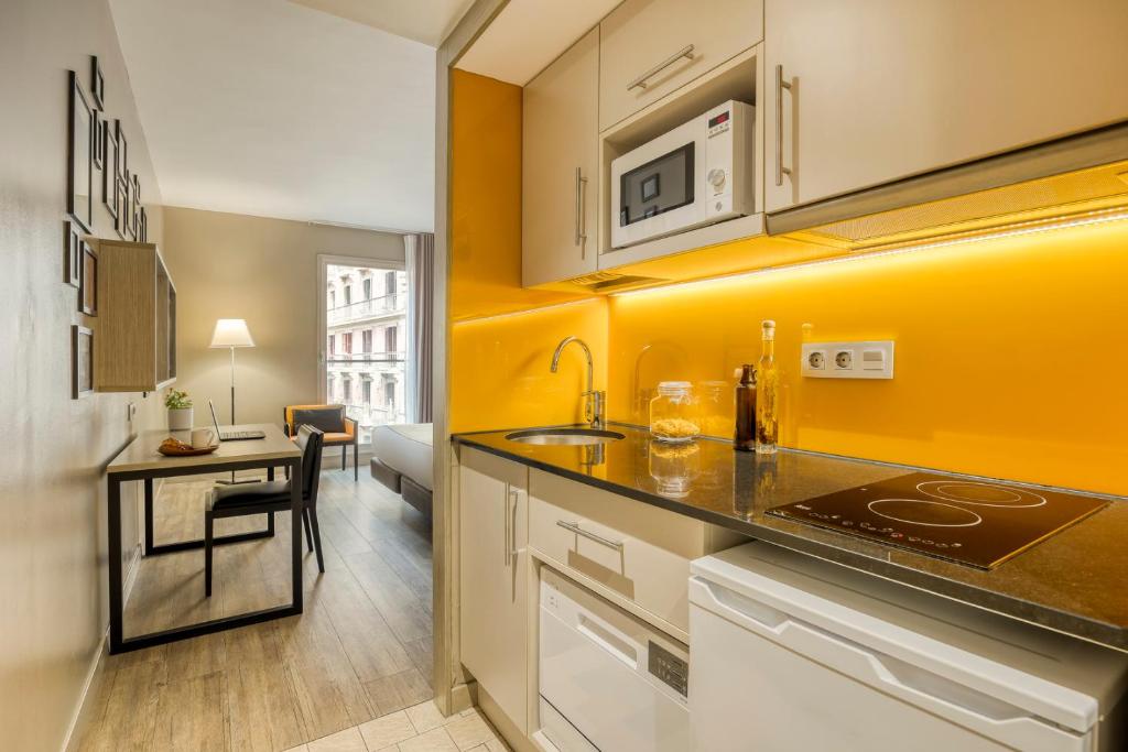a kitchen with a sink and a desk in a room at Citadines Ramblas Barcelona in Barcelona