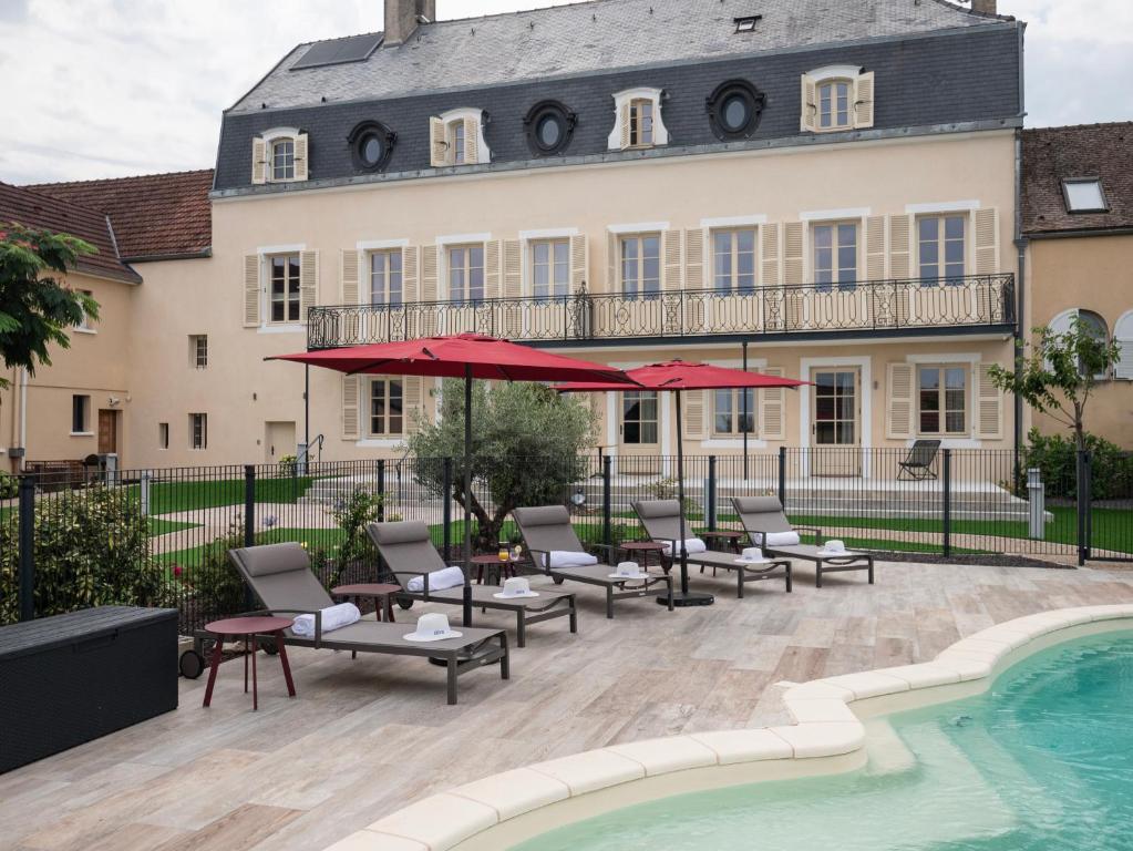 a patio with chairs and umbrellas next to a pool at La Maison de Jacqueline in Vosne-Romanée