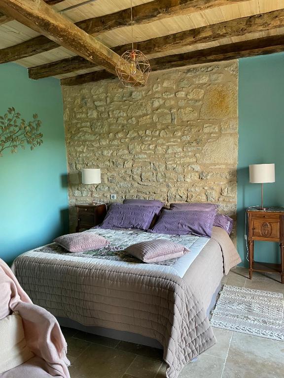 une chambre avec un lit avec un mur en pierre dans l'établissement Domaine de Galoubet Lot, à Beaumat