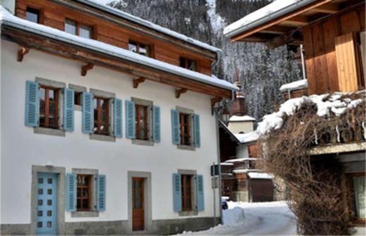 ein Gebäude mit blauen Fensterläden im Schnee in der Unterkunft Le Marti in Chamonix-Mont-Blanc