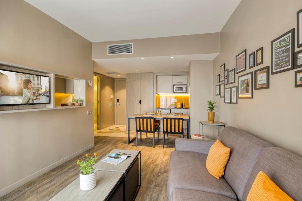 a living room with a couch and a table at Citadines Ramblas Barcelona in Barcelona