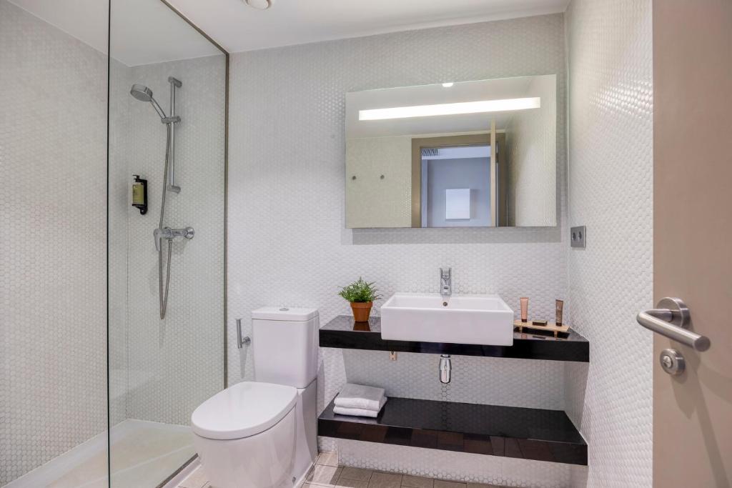 a bathroom with a sink and a toilet and a mirror at Citadines Ramblas Barcelona in Barcelona