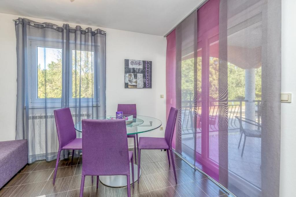 a dining room with purple chairs and a glass table at Apartments Kardumovic in Poreč