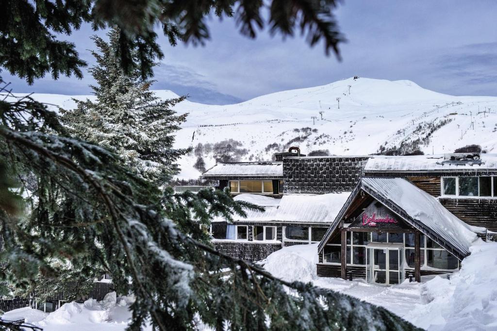 une maison recouverte de neige avec une montagne en arrière-plan dans l'établissement Belambra Clubs Superbesse - Le Chambourguet, à Super-Besse