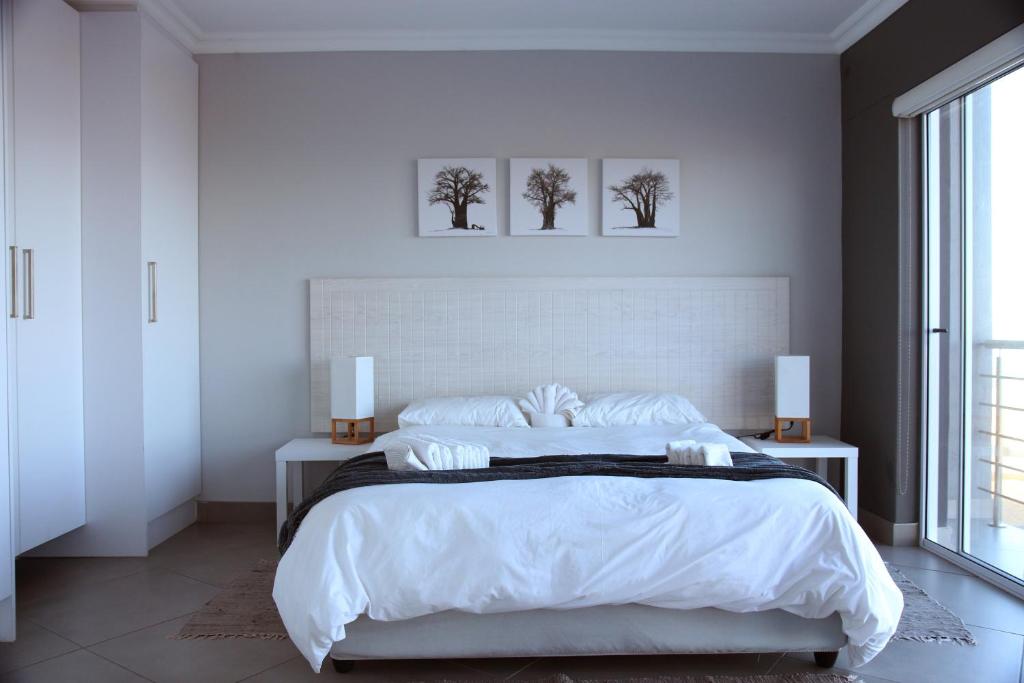 a white bedroom with a large bed with two pictures on the wall at Atlantic Dunes Unit 11, Self Catering in Rand Rifles