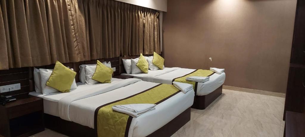 two beds in a hotel room with yellow pillows at Hotel Central Plaza in Siliguri
