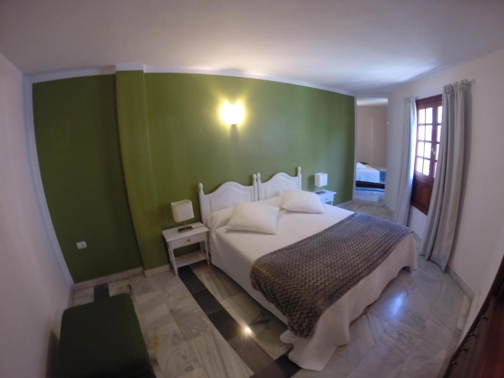 a bedroom with a bed with a green wall at Apartamentos Tapahuga in Playa de Santiago