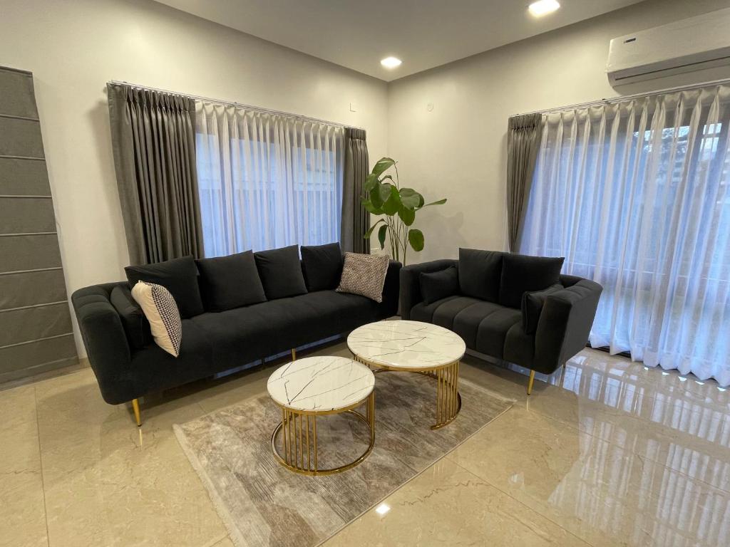 sala de estar con sofá negro y 2 mesas en Bridge Service Apartment, en Hyderabad