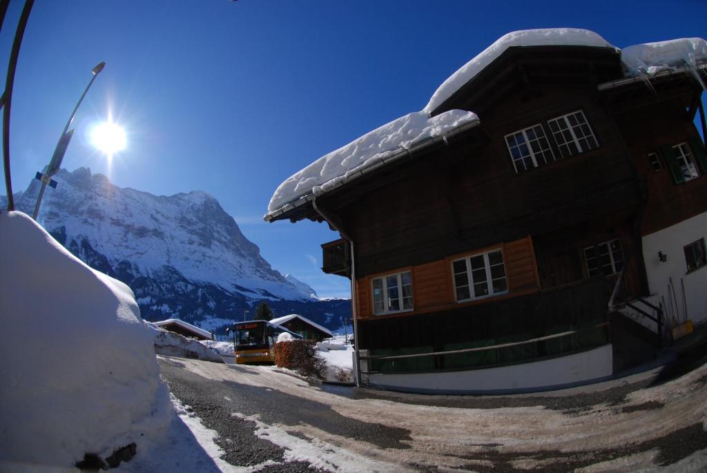 ein schneebedecktes Haus mit einem Berg im Hintergrund in der Unterkunft Chalet Tuftbach in Grindelwald