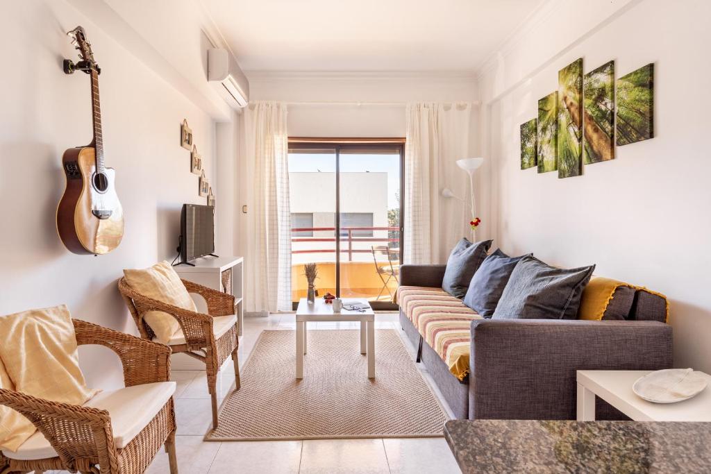 a living room with a couch and a guitar at ALTIDO Deluxe apt with terrace in Costa da Caprica in Costa da Caparica