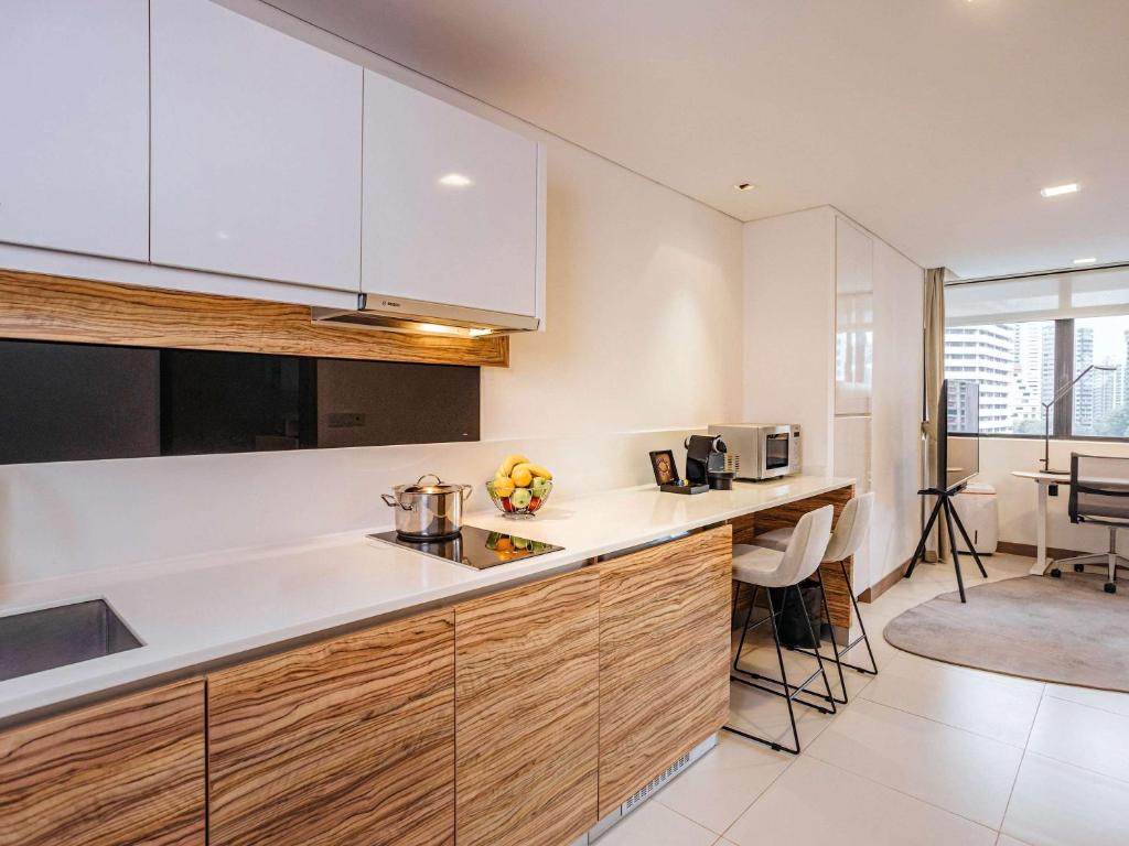 a kitchen with white cabinets and a counter top at Novotel Living Singapore Orchard in Singapore