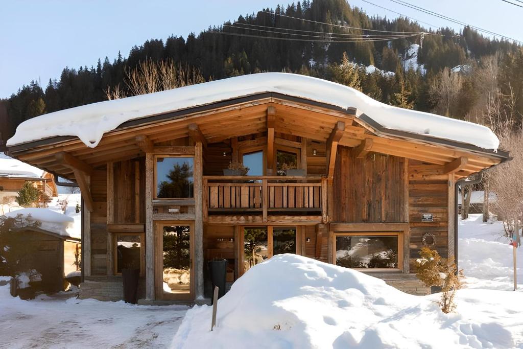 una baita di tronchi con neve sul tetto di Alpine Chalet a Megève