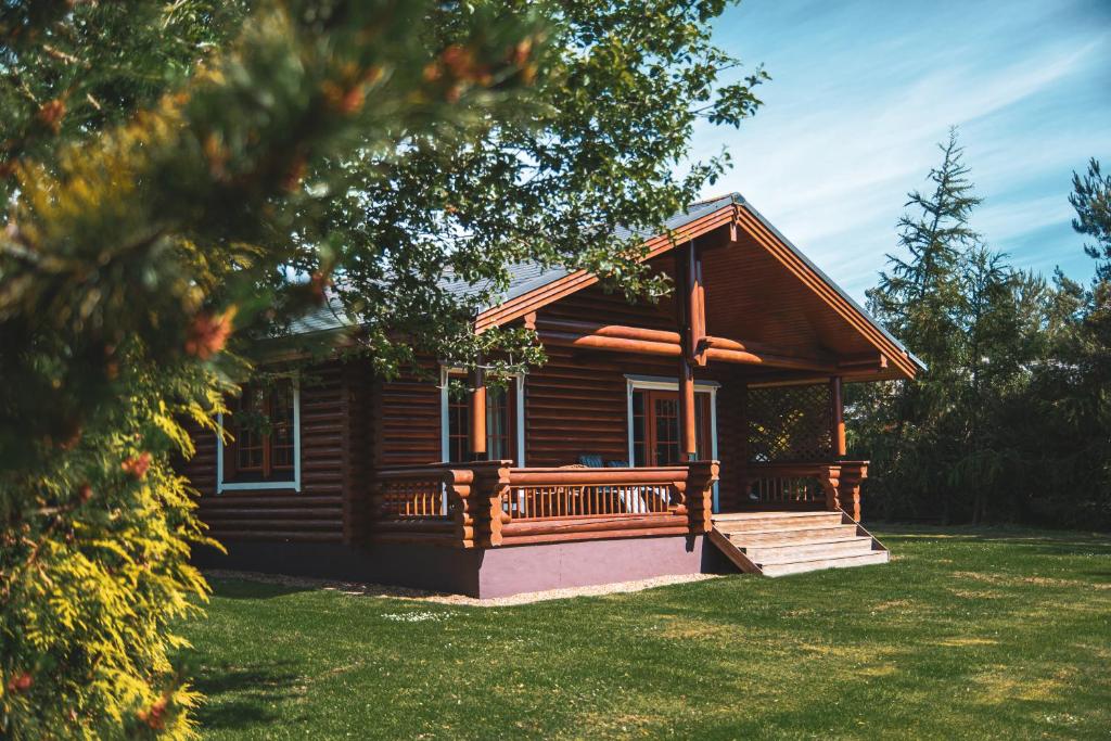 a log cabin with a porch and a bench at Strathisla - Luxury Two Bedroom Log Cabin with Private Hot Tub & Sauna in Berwick-Upon-Tweed