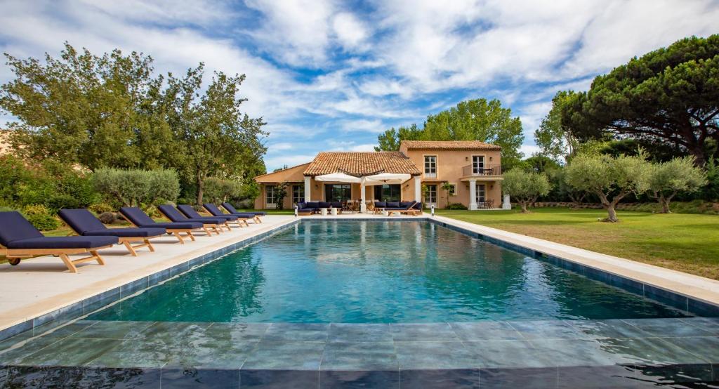 une piscine avec des chaises et une maison dans l'établissement Sumptuous Villa facing the Bay of Canebiers, à Saint-Tropez
