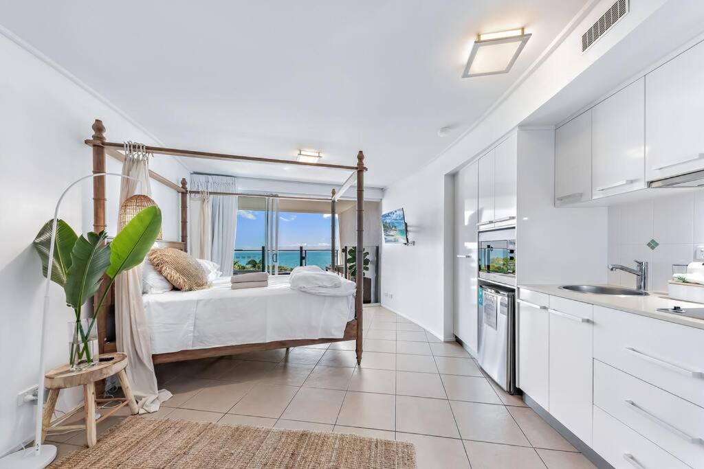 a bedroom with a bed with a view of the ocean at Three A Airlie Seaviews, Pool, Private Spa in Airlie Beach