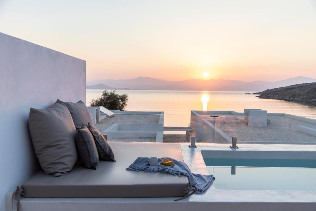 a couch with pillows and a sunset in the background at Citadela Paros Molos - Beachfront Maisonette with Plunge Pool in Molos Parou