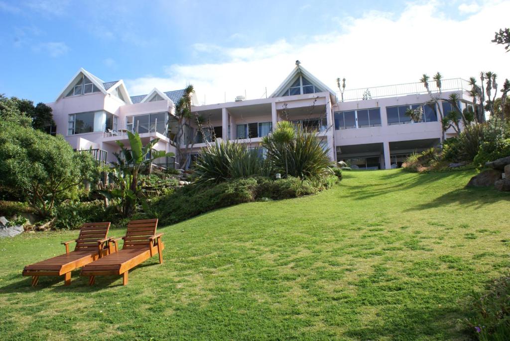 twee banken voor een groot gebouw bij The Pink Lodge on The Beach in Wilderness