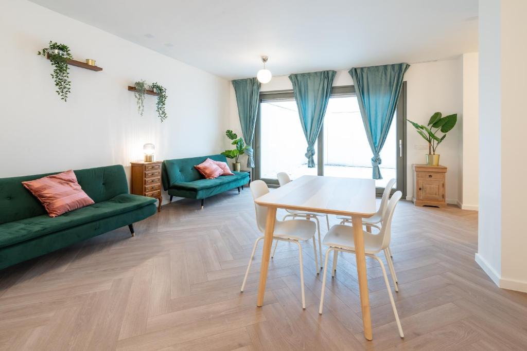 uma sala de estar com uma mesa e um sofá verde em City Centre Loft Residence em Antuérpia