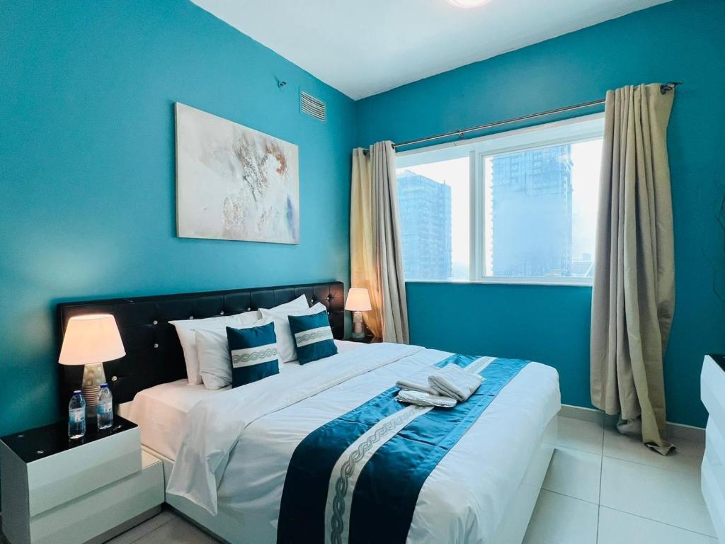 a blue bedroom with a large bed and a window at SKY NEST HOMES PRIVATE 1 BEDROOM APARTMENT DUBAI MARINA in Dubai