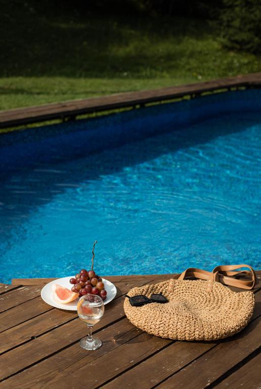 a glass of wine and a plate of fruit next to a pool at Dolyna Mykolaya in Migovo