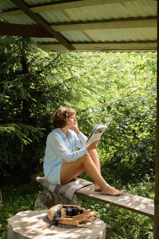 a woman sitting on a bench reading a book at Dolyna Mykolaya in Migovo