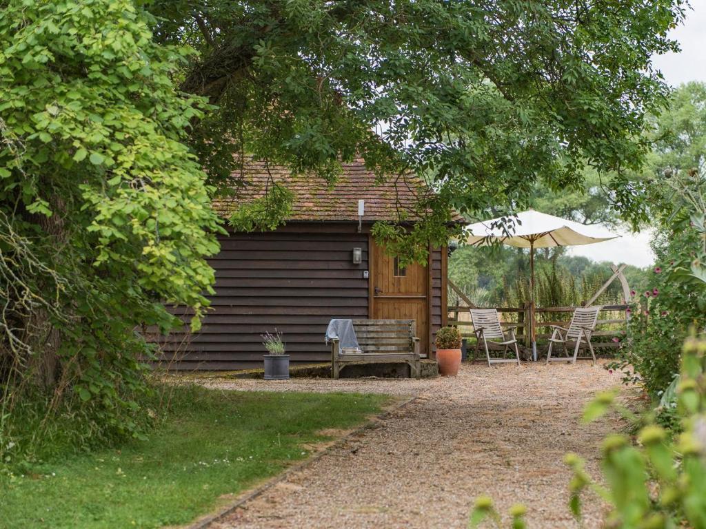 a cabin with a bench and an umbrella at Heron Barn in Hollingbourne