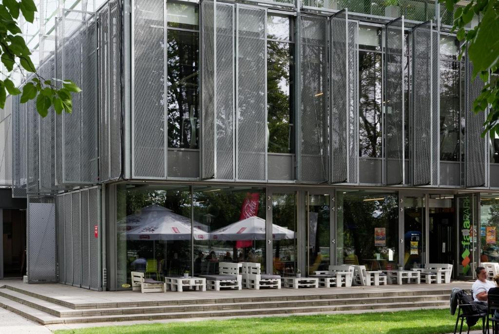 un edificio de cristal con mesas y sombrillas. en Fala Park en Wolsztyn