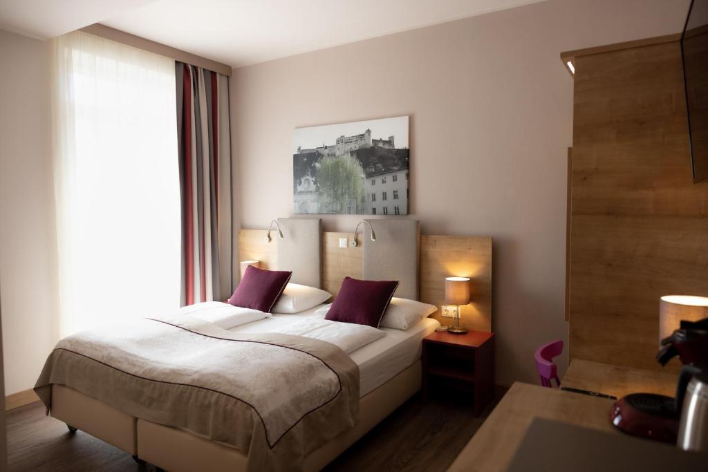 a bedroom with a bed and a large window at Hotel Max 70 in Salzburg