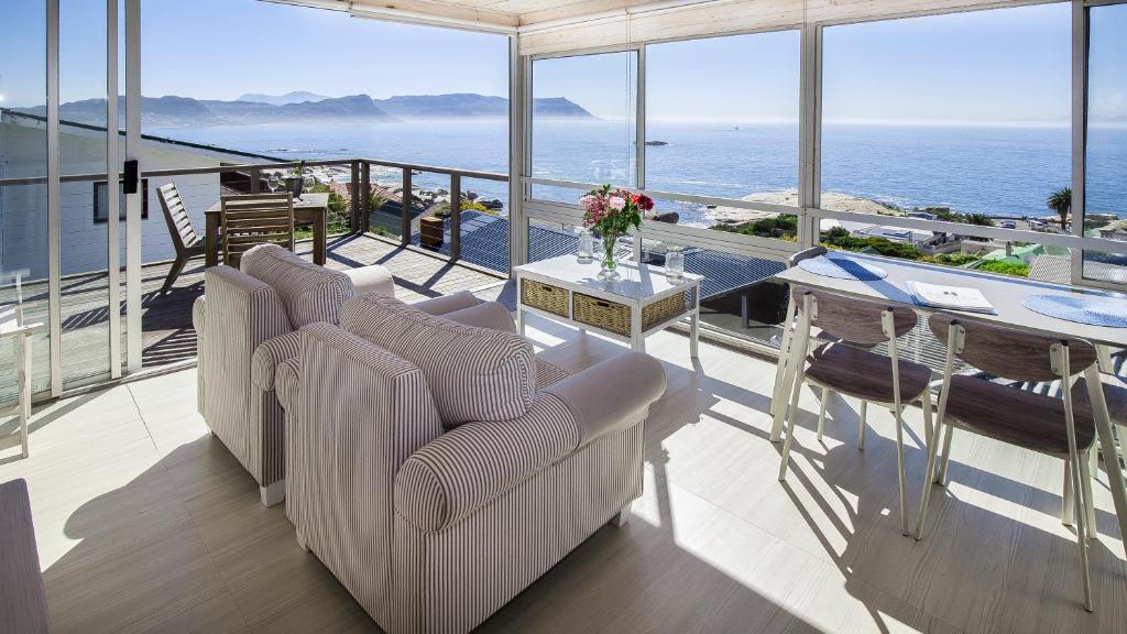 uma varanda com duas cadeiras e uma mesa e o oceano em Penguins View Guesthouse em Simonʼs Town
