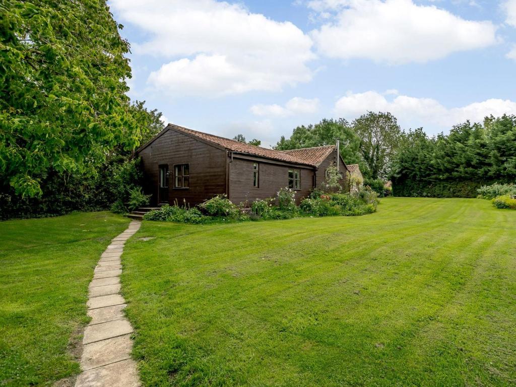 una casa en un patio con un campo de hierba en Orchard Barn, en Meare