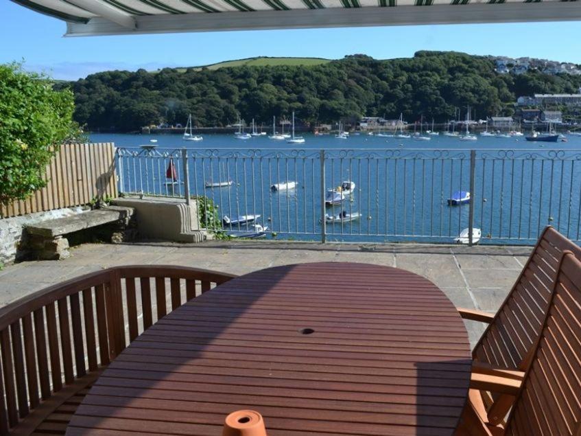 a wooden bench on a deck with a view of a harbor at Roadstead in Fowey