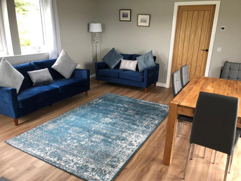 a living room with two blue couches and a table at Loch Caroy Bay Cottage in Ose