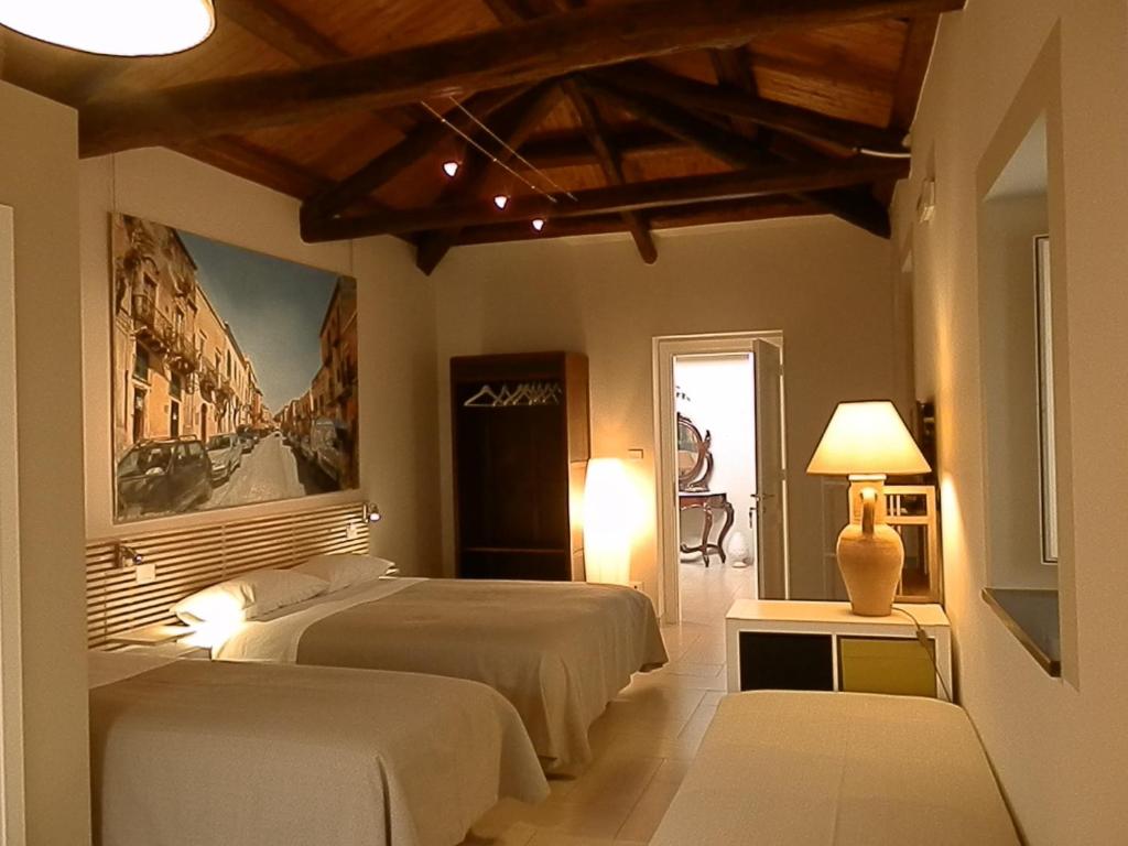 a bedroom with two beds and a painting on the wall at B&B Re Umberto in Milazzo