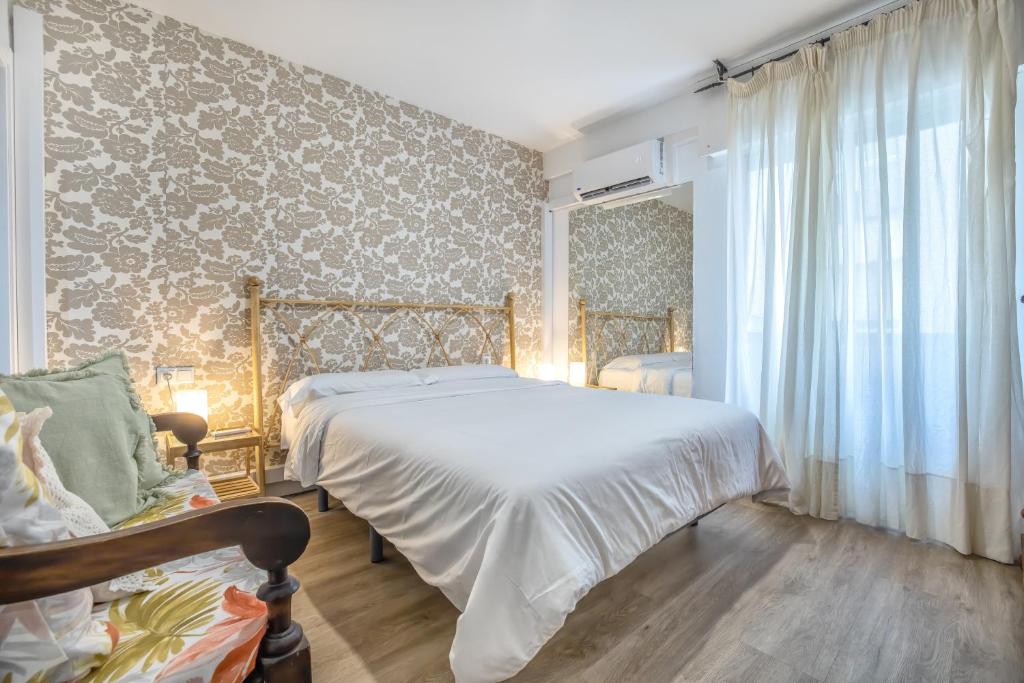 - une chambre avec un lit et un mur orné de papier peint floral dans l'établissement Apartamento Centro Cordoba & Parking Gratuito, à Cordoue