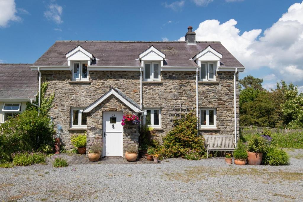 an old stone house with a white door at Stable Cottage - QC1789 in Llandyssiliogogo