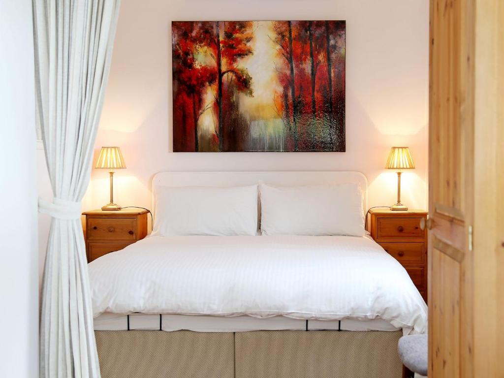 sypialnia z białym łóżkiem i 2 lampami w obiekcie Garden Cottage w mieście Icklesham