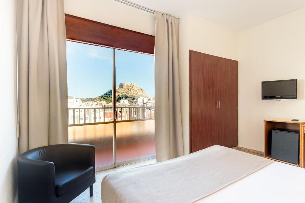 a hotel room with a bed and a chair and a window at Hotel Leuka in Alicante