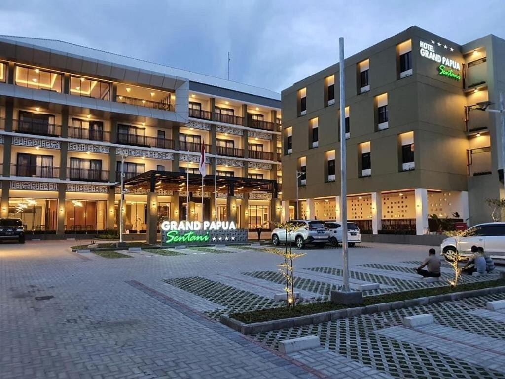 un gran edificio con coches estacionados frente a él en Grand Papua Hotel Sentani, en Weversdorp
