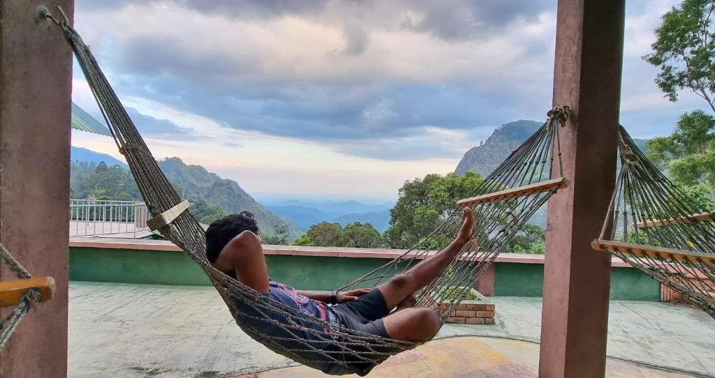a woman laying in a hammock overlooking mountains at Hilltop Guest House in Ella
