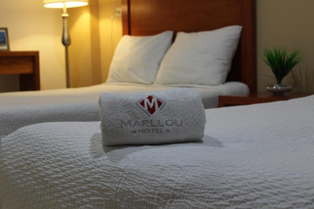 Una habitación de hotel con una cama blanca con una toalla. en Hotel Marllou en Xalapa