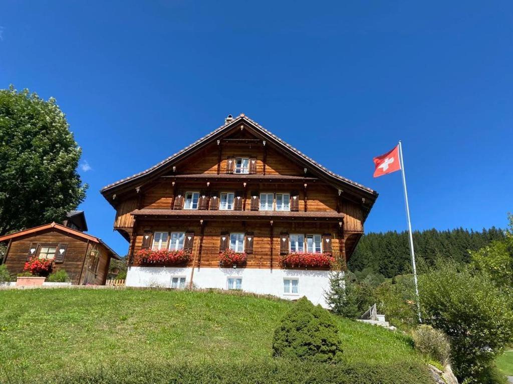 a large wooden house with a flag in front of it at Ybrig Lodge in Unteriberg