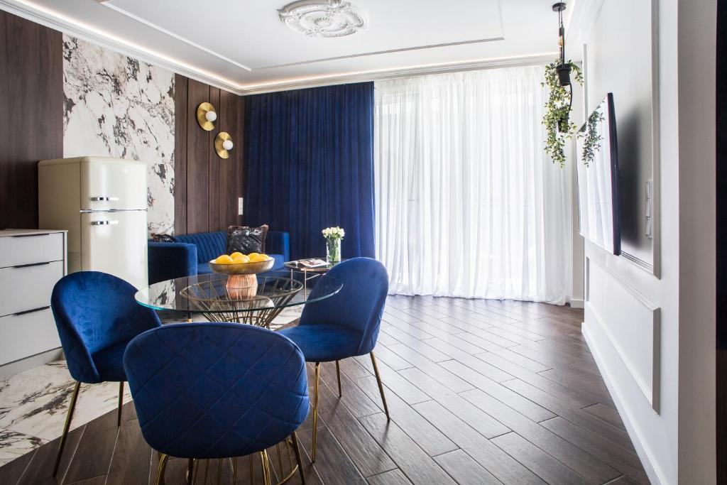 uma sala de jantar com cadeiras azuis e uma mesa de vidro em Luksusowy Apartament Przy Filharmonii em Katowice